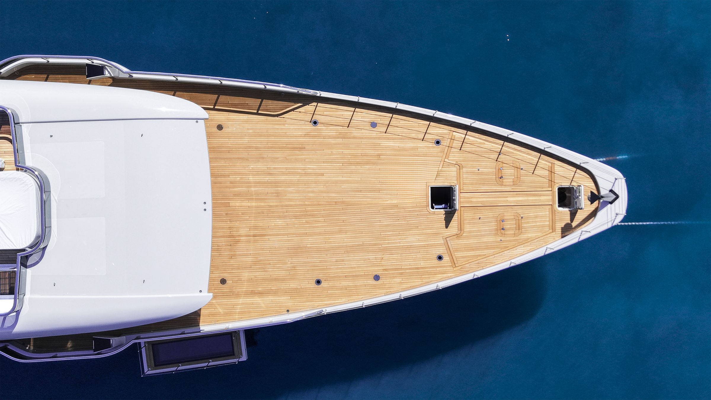 Aerial view over the teak bow of a luxury yacht in deep blue water
