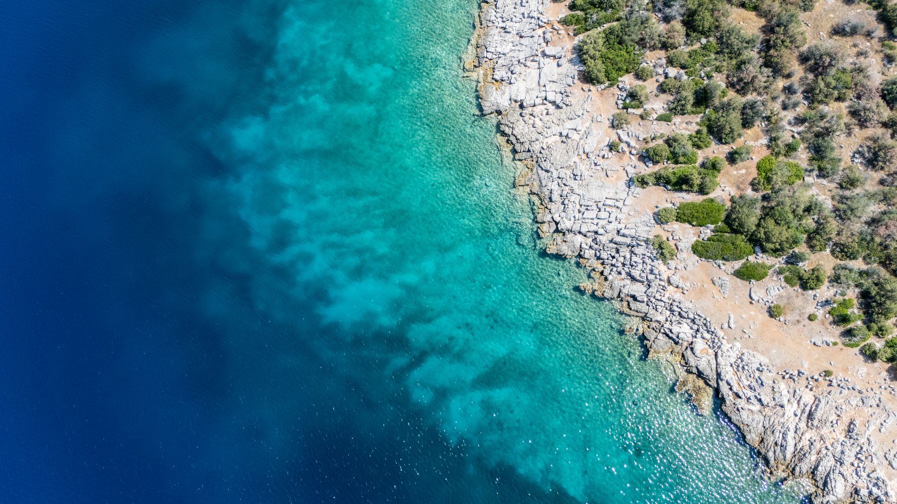 Clear turquoise Mediterranean water beside a rocky Greek coast